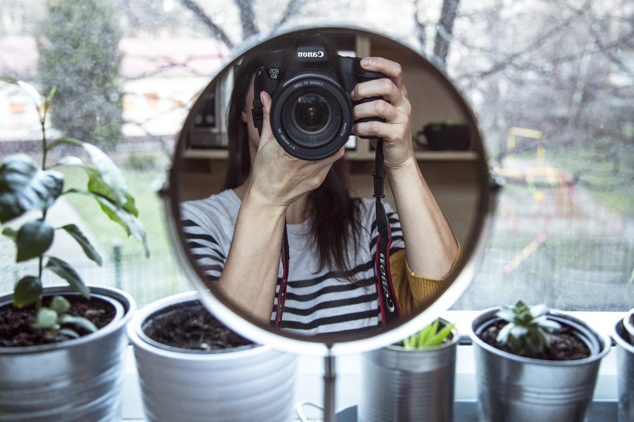 Fille se photographie à travers un miroir